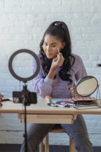 woman applying concealer to her face while looking in a small mirror