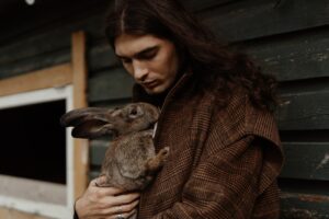 man in brown coat holding a rabbit