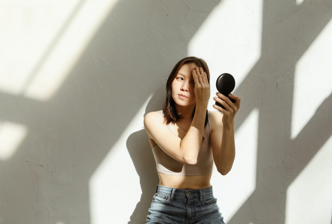 woman in shadows applying makeup